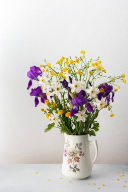 Bir buket bahar çiçeği, süsen çiçekleri ve beyaz nergisli sarı ranunculusla ev içi.