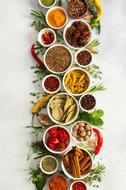 Gri arka planda güzel bir yemek pişirme baharatları ve kurutulmuş otlar, doğal renklerde bir palet sunar.