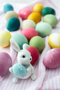 Çok renkli Paskalya yumurtaları, pembe masa örtüsü üzerinde dekoratif tavşanlar, Paskalya tatiliniz kutlu olsun.