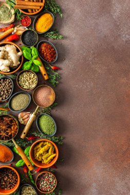 Baharat ve otların uyumlu bir karışımı, renkler ve kokularla dolu, kahverengi bir arka plana yayılmış, aşçılık sanatını çağrıştırıyor.