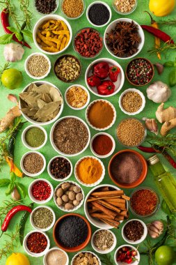 Renkli baharatlar ve bitkiler narin yeşil bir zemin üzerine dizilmiş canlı doğal bir görünüş için tazeliklerini ve kokularını vurguluyorlar.