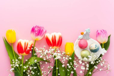 İlkbahar Paskalya arkaplanı, çok renkli Paskalya yumurtaları ve pembe arka planda çigila olan laleler, kopyalama alanı.