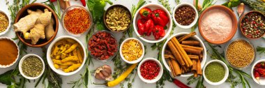 Gri bir arka planda sıralanmış çeşitli baharat ve otlar, her yemeğe derinlik ve aroma katan doğal tonlara sahip, afiş