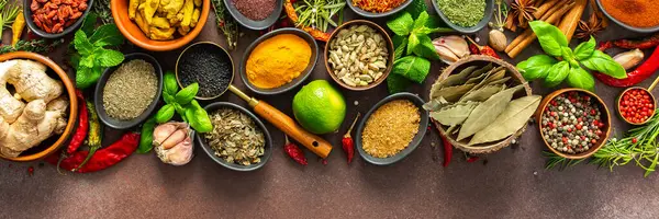 Kahverengi bir arka planda dinlenen renkli baharat ve otlardan oluşan zengin bir palet. Tazelik ve aroma yayıyor. Gurme ilham kaynağı ve afiş için mükemmel.