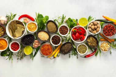 Gri arka planda çeşitli baharat ve otlardan oluşan bir koleksiyon. Lezzetli ve dokulu yemekleri geliştirmek için mükemmel.