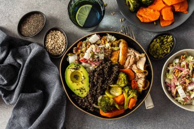 İçinde kinoa, avokado, kızarmış tavuk, patates, kabak ve brokoli gibi taze lahana ve turp salatası ile tamamlanmış kızarmış sebzeler bulunan besleyici, sağlıklı bir kahvaltı.