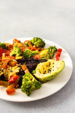 Domates, kabak, biber ve soğan gibi haşlanmış sebzeli siyah pirinç, domates, brokoli ve turplu taze salata, susam tohumlu avokado.