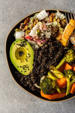 İçinde kinoa, avokado, kızarmış tavuk, patates, kabak ve brokoli gibi taze lahana ve turp salatası ile tamamlanmış kızarmış sebzeler bulunan besleyici, sağlıklı bir kahvaltı.