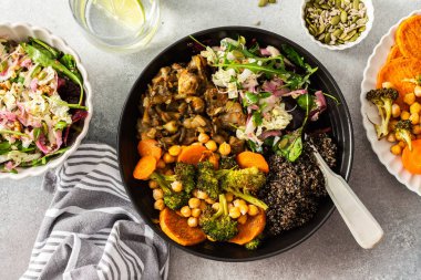 İçinde siyah kinoa, avokado, kızarmış tavuk, tatlı patates, kabak ve brokoli bulunan besleyici bir kahvaltı kasesi. Lahana, turp, chia ve susam tohumlarıyla birlikte.