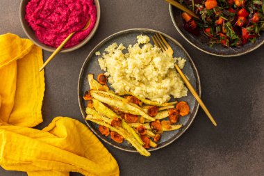 Bu besleyici yemek darı, taze mevsimlik sebze ve otlardan oluşan canlı bir salata ile tamamlanmış fırında kabak ve havuçla birlikte nohut çörekleri ve kremalı pancar humusu içerir.