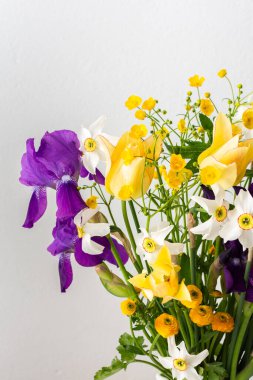 Evin içinde bir buket bahar çiçeği, süsen çiçekleri ve sarı ranunculus, beyaz nergisli sarı laleler