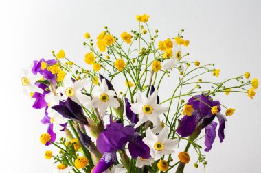 Bir buket bahar çiçeği, süsen çiçekleri ve beyaz nergisli sarı ranunculusla ev içi.