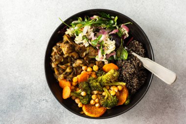 İçinde siyah kinoa, avokado, kızarmış tavuk, tatlı patates, kabak ve brokoli bulunan besleyici bir kahvaltı kasesi. Lahana, turp, chia ve susam tohumlarıyla birlikte.