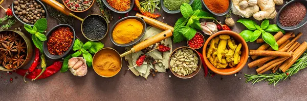 Kahverengi bir arka planda dinlenen renkli baharat ve otlardan oluşan zengin bir palet. Tazelik ve aroma yayıyor. Gurme ilham kaynağı ve afiş için mükemmel.