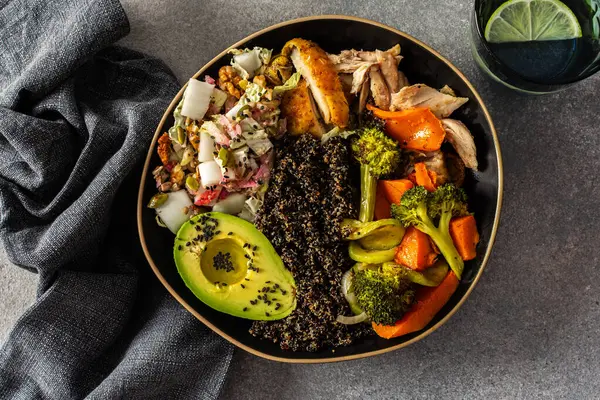 İçinde kinoa, avokado, kızarmış tavuk, patates, kabak ve brokoli gibi taze lahana ve turp salatası ile tamamlanmış kızarmış sebzeler bulunan besleyici, sağlıklı bir kahvaltı.