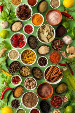 Renkli baharatlar ve bitkiler narin yeşil bir zemin üzerine dizilmiş canlı doğal bir görünüş için tazeliklerini ve kokularını vurguluyorlar.