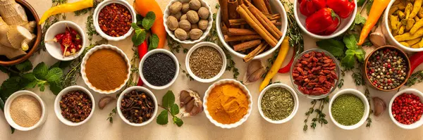 Değişik baharatlar ve kurutulmuş otlar bej bir zemin üzerine dizilmiştir. Mutfak çeşnisi ve aromatik, afişle zenginleştirilmiş yemekler için gereklidir.