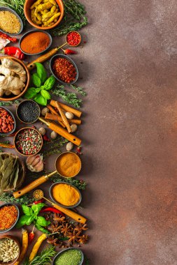 Baharat ve otların uyumlu bir karışımı, renkler ve kokularla dolu, kahverengi bir arka plana yayılmış, aşçılık sanatını çağrıştırıyor.