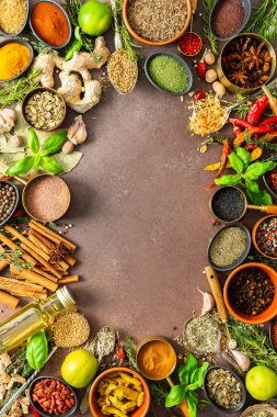 Sıcak kahverengi bir arka planda çeşitli kokulu bitkiler ve baharatlar, görsel çeşitliliklerini gösteren aromatik cazibe, baharat çerçevesi