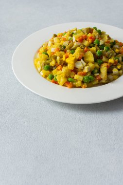 Bu yemekte haşlanmış yumurtadan, taze tavuk göğsünden, doğranmış patatesten, tatlı havuçtan ve taze taze bezelyeden oluşan canlı bir salata var..