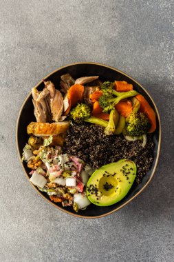 Üzerinde taze lahana ve turp salatası olan dengeli bir kahvaltı kasesi, avokado, kızarmış tavuk ve tatlı patates.