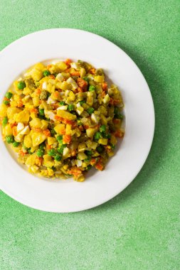 Renkli salata haşlanmış yumurta, tavuk göğsü, doğranmış patates, havuç ve yeşil bezelye karışımı ve zeytinyağı ile karıştırılmış, sağlıklı bir yemek için mükemmel.