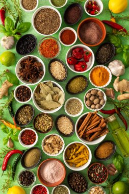 Renkli baharatlar ve bitkiler narin yeşil bir zemin üzerine dizilmiş canlı doğal bir görünüş için tazeliklerini ve kokularını vurguluyorlar.