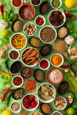 Renkli baharatlar ve bitkiler narin yeşil bir zemin üzerine dizilmiş canlı doğal bir görünüş için tazeliklerini ve kokularını vurguluyorlar.