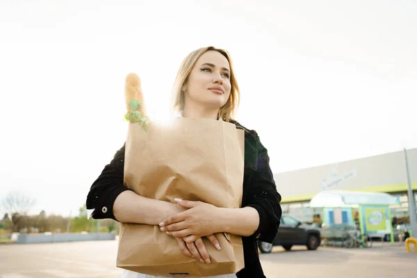Elinde içi taze ve sağlıklı şeylerle dolu kağıt poşetler tutan kadınlar, onların gerçek gülümsemeleri süpermarketten alışveriş yapmanın memnuniyetini yansıtıyor..