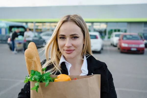 Taze ve sağlıklı şeylerle dolu kağıt torbaları tutan kadınların mutluluğu, onların gerçek gülümsemeleri süpermarketten alışveriş yapmanın memnuniyetini yansıtıyor..