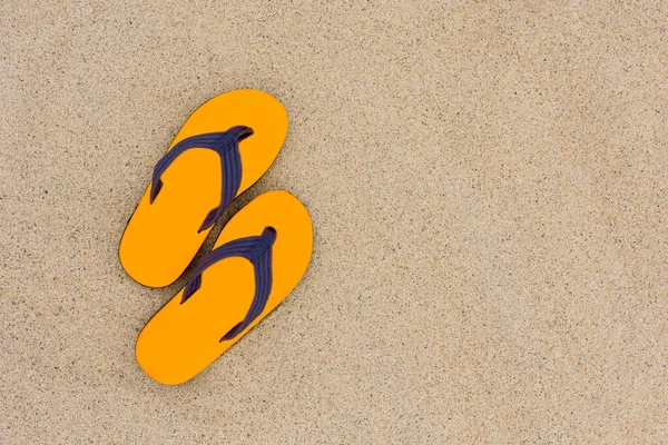 Güzel bir kumsalın kumlarında bir çift turuncu parmak arası terlikle seyahat etmek..