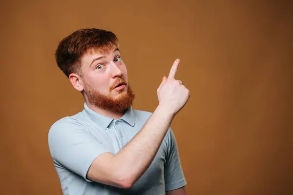 Sakallı adam parmağıyla işaret ediyor, kolunu gökyüzüne kaldırıyor.