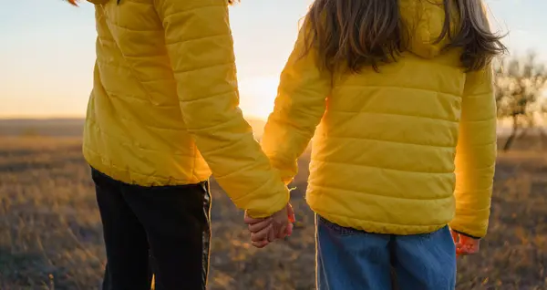 Sarı ceketli iki çocuk gün batımında bir tarlada el ele yürür. Arkadaşlık ve masumiyet gösterirler.