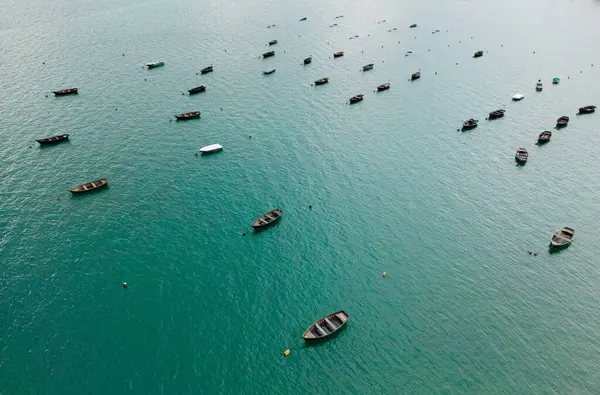 Bir hava manzarası sakin, berrak mavi sularda huzurlu ve huzurlu bir ortamda birkaç teknenin sakin manzarasını yakalar.