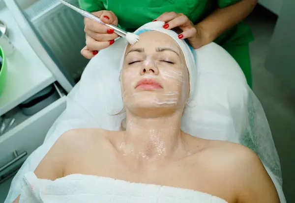 Güzellik kaplıcası sırasında yüzü gençleştirici bir maskeyle kaplanmış bir kadın yüzü..