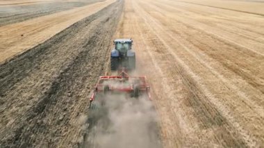 Güçlü bir traktör, güneşli koşullar altında geniş bir tarım arazisinde zengin ve verimli toprağı sürüyor.