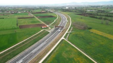 Manzaralı bir hava perspektifi manzaralı bir güzergahın tarlaları ve otobanı olan yemyeşil kırsal alanları geçtiğini gösteriyor.