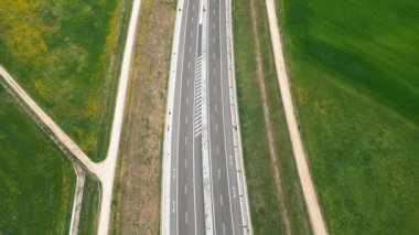 Yüksek irtifa manzaralı, yemyeşil alanlar ve patikalarla çevrili, bakımlı, boş bir otoyol..