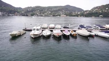 Huzurlu ve huzurlu bir göl kenarı boyunca çeşitli renkli teknelerin sergilendiği güzel ve resimsel bir manzara.