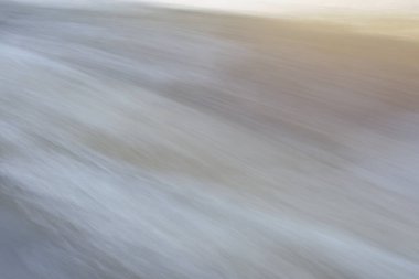 Dynamic texture of fast moving water, in pastel pale neutral tones. Concepts of nature and motion.
