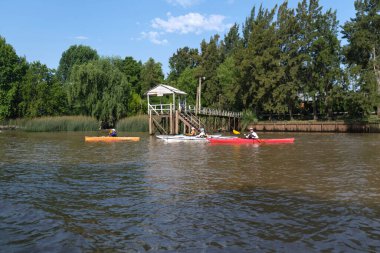 Tigre, Buenos Aires, Argentina, Jan 11 2022: people kayaking along a navigable waterway in the Tigre delta, a tourist destination for weekend getaways, a sunny summer day.