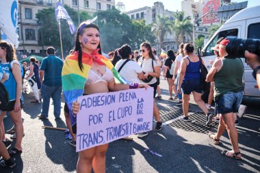 Buenos Aires, Arjantin; 8 Mart 2023: Uluslararası Kadınlar Günü. Omuzlarında gökkuşağı bayrağı olan genç bir kadın trans, travesti ve ikili olmayan işçi kotasına tam destek veriyor.