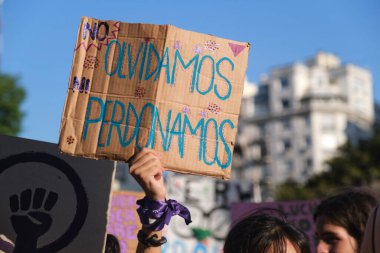 Buenos Aires, Arjantin; 8 Mart 2023: Uluslararası Kadınlar Günü. Elinde bir poster tutan tanınmamış bir kadın: ne unuturuz ne de affederiz.