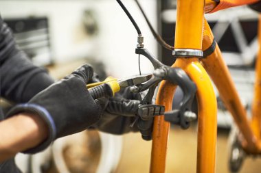 Bisikletin bakımı: tanınmayan birinin eldiven takıp atölyesinde bisiklet freni kesmesi..