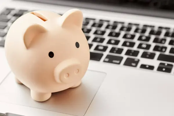Piggy bank on a laptop. Concepts: savings, digital economy and technology. Bright composition with copy space.