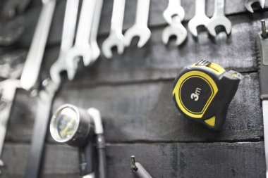 Ölçüm bandı, anahtarlar ve bisiklet tamirhanesinde bir alet tahtasına asılı diğer aletler. Seçici odak ile görünümü kapat.