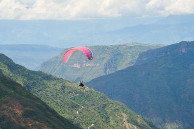 Paragliding in the Chicamocha Canyon area, Santander, Colombia. Paraglider flying enjoying the spectacular view of the surrounding mountain scenery. clipart