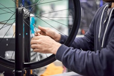 Bisiklet atölyesindeki bisiklet tekerleğinin gerilimini ölçen tanınmamış bir adam. İş yerindeki gerçek insanlar.