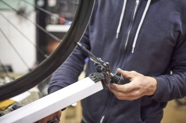 Bisiklet atölyesinde bakım hizmeti: tanınmayan bir kişi bisiklet tekerleğini doğru dürüst bir duruş kullanarak hizalıyor. İş yerindeki gerçek insanlar.