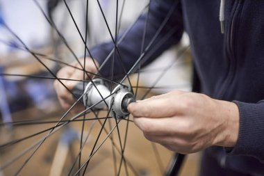 Unrecognizable man assembling a bike wheel axle after disassembling it for cleaning and greasing as part of a bicycle maintenance service. Real people at work. clipart